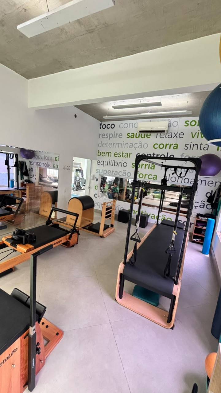 Outra vista da sala de Pilates em Moema, com aparelhos, bolas de Pilates e frases motivacionais na parede