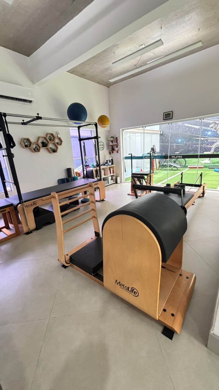 Aparelho de Pilates com arco estofado e escada de madeira na sala de Moema, com janela de vidro ao fundo