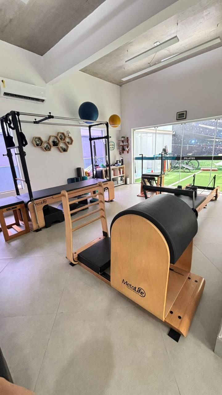 Sala de Pilates em Moema vista de um canto, com aparelhos de madeira, bolas penduradas e prateleiras