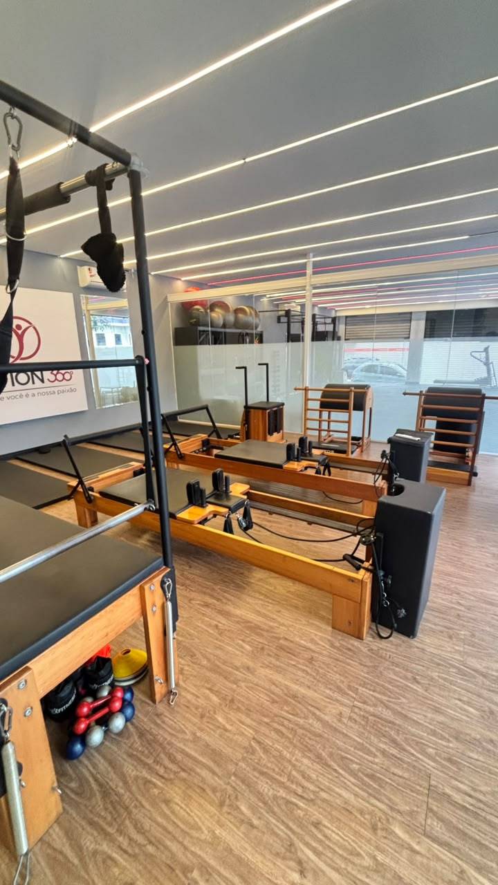 Sala de Pilates em Vila da Saúde com aparelhos de madeira, piso de madeira e iluminação em linhas no teto